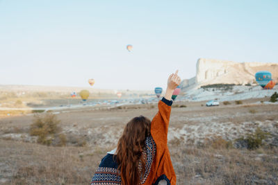 Rear view of woman with arms outstretched standing at beach