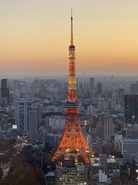 Illuminated buildings in city against sky during sunset