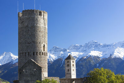 Low angle view of historical buildings against snowcapped mountains