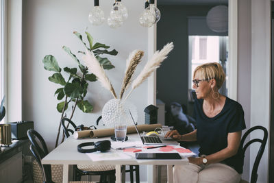 Woman working at home sitting at table reading on laptop screen