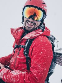 Portrait of man with red umbrella standing in snow