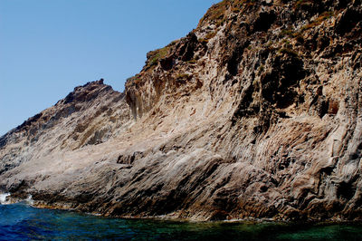 Rock formations by sea against clear sky