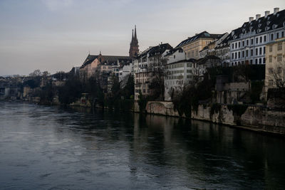 Buildings by river against sky