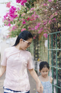 Mother holding daughter's hands while walking at park