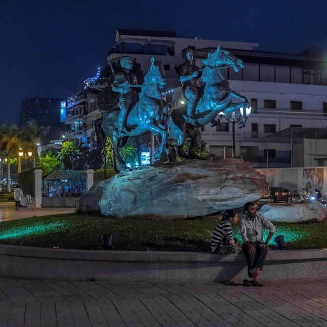 building exterior, architecture, built structure, full length, night, lifestyles, art and craft, art, men, human representation, leisure activity, creativity, blue, statue, casual clothing, rear view, illuminated, sculpture