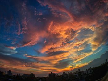 Low angle view of buildings against dramatic sky during sunset