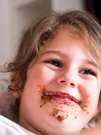 Close-up of cute girl with cake on her face at home