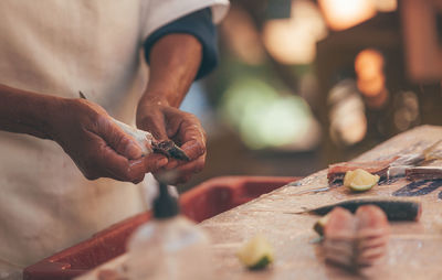 An old lady preparing some fish at table with lemons