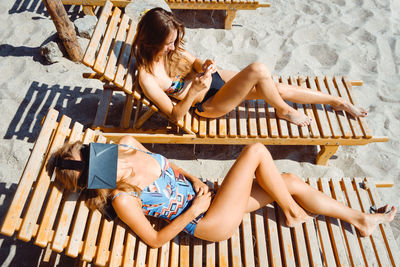 Female friends sitting on lounge chairs at beach