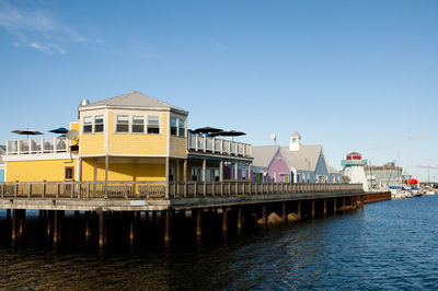 Buildings by river against blue sky