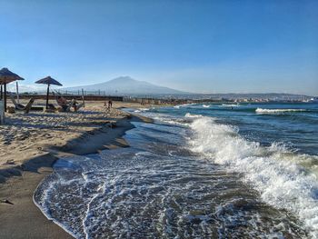 Scenic view of beach against clear blue sky and mount etna