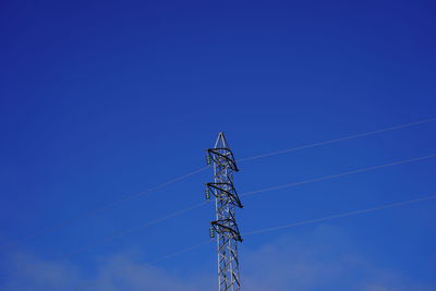 Low angle view of electricity pylon against clear blue sky