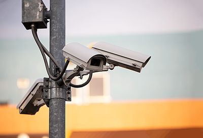 Close-up of security camera on pole against sky