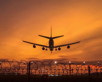 Low angle view of silhouette airplane against sky during sunset