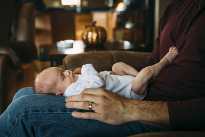 Cute daughter lying on father's laps at home