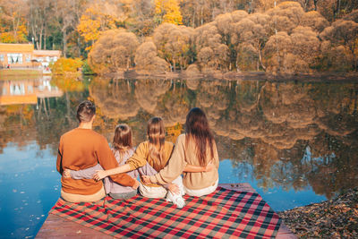 Group of people sitting on rock with reflection in water