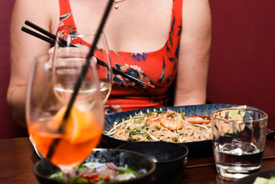 Midsection of woman holding drink on table