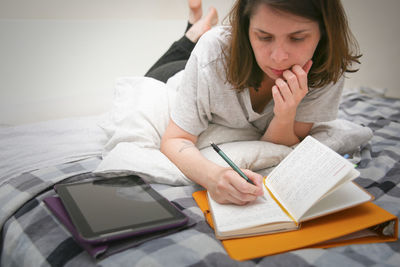 Midsection of woman reading book in bed