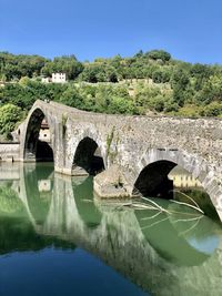 Arch bridge over river against sky