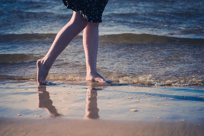 Low section of woman walking at beach