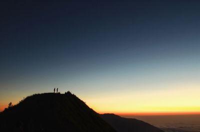 Silhouette people standing on mountain against sky during sunset