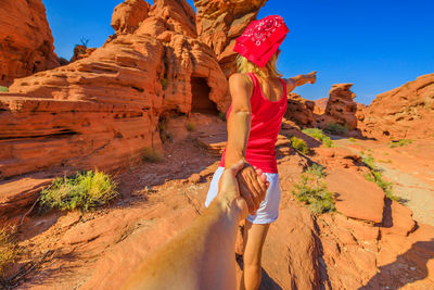 Cropped image of man holding mature woman hand on rock formation at desert