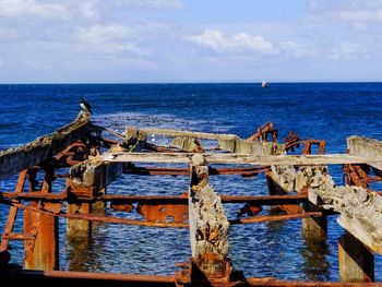Broken pier in sea against sky