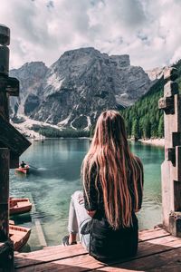 Rear view of woman looking at lake against mountain range