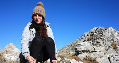 Portrait of woman sitting on mountain against sky