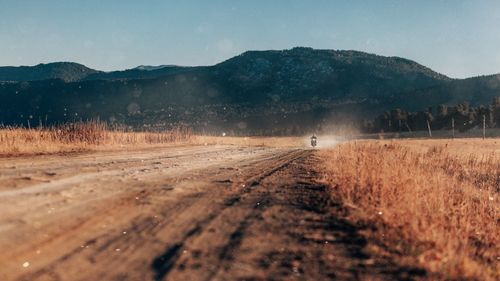 Surface level of road amidst field against sky