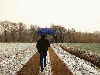 Rear view of man walking on snow covered landscape