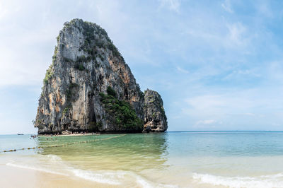 Rock formation on beach against sky