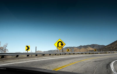 Road leading towards mountains against clear sky seen through car windshield