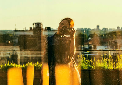 Portrait of man standing by glass window in rain