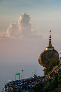 Crowd at temple against sky during sunset in city