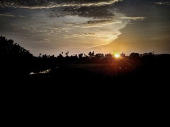 Silhouette trees on landscape against sky at sunset