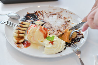 Close-up of hand holding ice cream served in plate