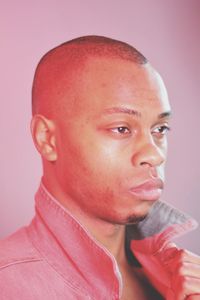 Close-up of serious man looking away against colored background