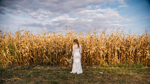 Rear view of woman standing on field against sky