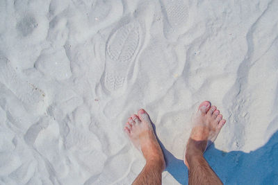Low section of man relaxing on sand at beach