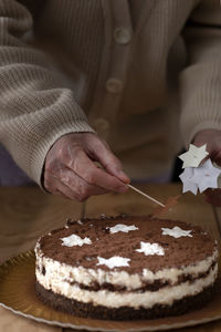A female hand removes a star after sprinkling a cake with powdered sugar.