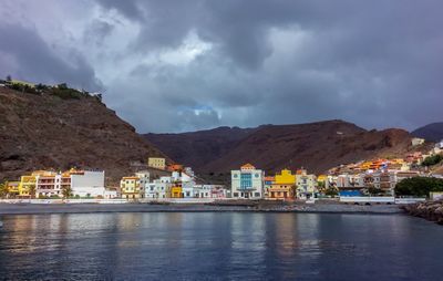 Houses by lake against sky in city