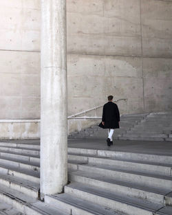Rear view of man walking on staircase