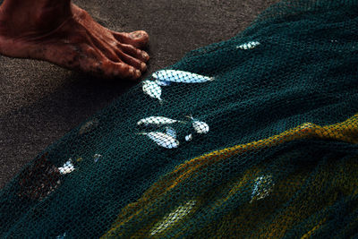 Low section of man by fishing net and dead fish at beach