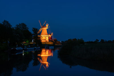 Scenic view of canal with traditional windmill reflection at night