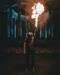 Man holding fire while standing on road at night
