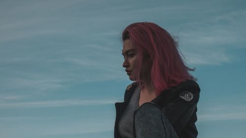 Young woman with dyed hair against sky during sunset