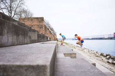 Side view of male athletes jumping on steps at beach