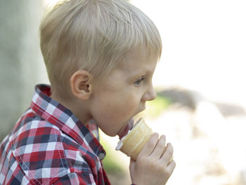 Side view of cute boy licking ice cream 