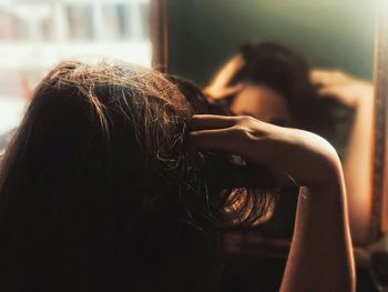 Woman adjusting hair reflecting on mirror